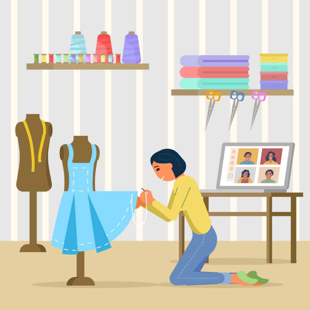 a seamstress kneeling in front of a dress form hemming a blue halter dress