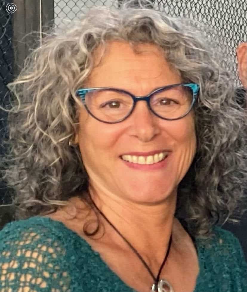 profile picture of a smiling woman with glasses and curly hair